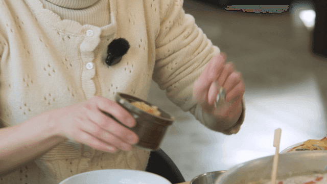 Woman putting minced garlic into seasoning bowl