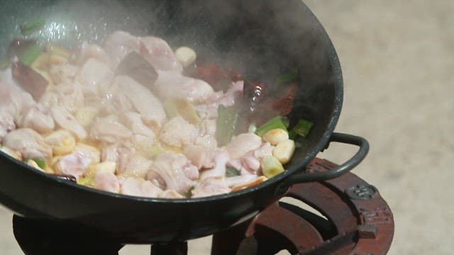 큰 웍에서 센 불로 채소와 고기를 볶는 모습