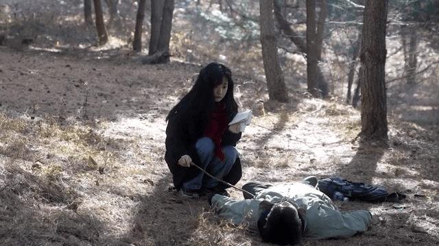 숲 속에서 쓰러져 있는 남성을 깨우려는 여성