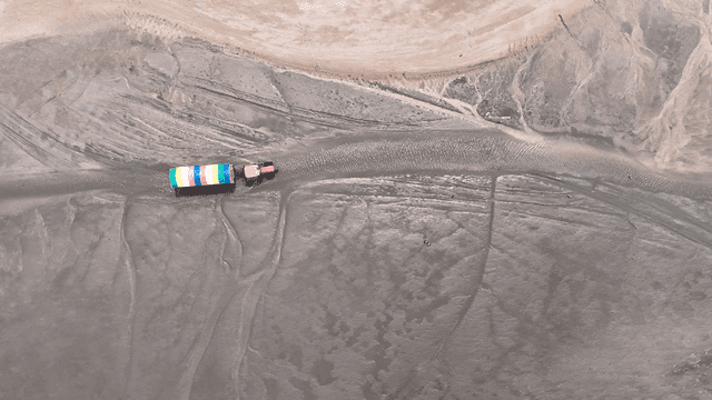 Tractor pulling colorful trailer on mudflats