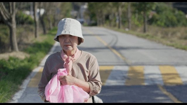 Elderly woman walking down a country road looking back