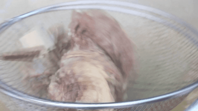 Beef soup meat and bones lifted with strainer