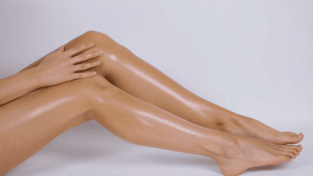 Hands applying lotion to smooth legs
