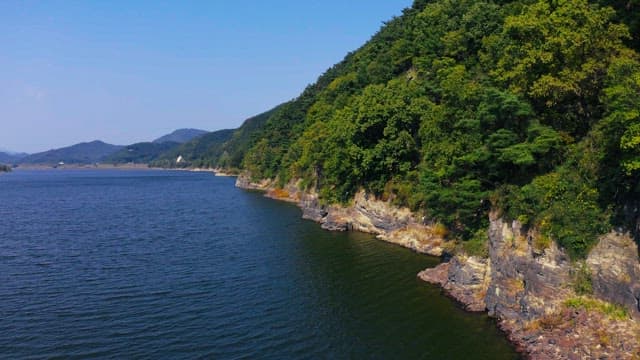 Scenic view of forested cliffs along a river on a sunny day