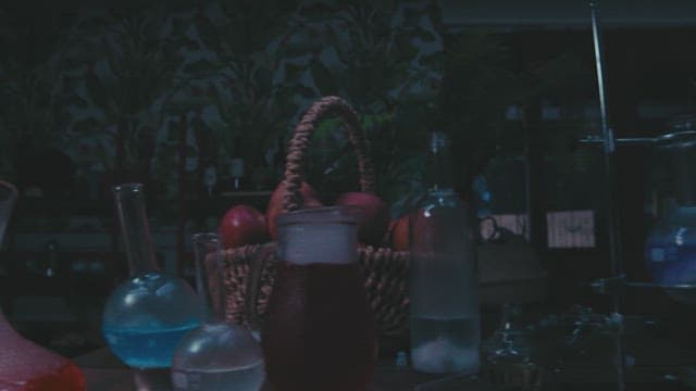 어둡게 조명된 연구실에서 돋보기로 사과를 조사하는 남자