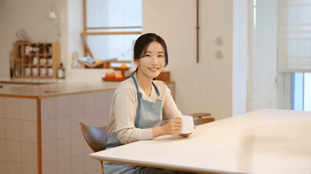 Woman smiling while holding coffee at table