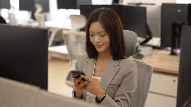 Female office worker looking at her smartphone in office