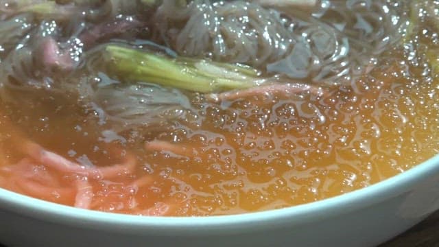 젓가락으로 냉면을 들어 올리는 장면