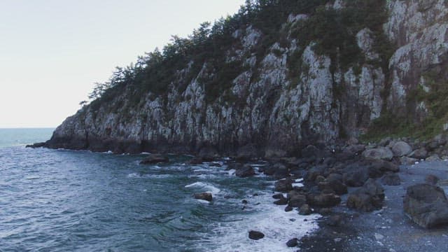 Rocky cliff by the ocean with waves