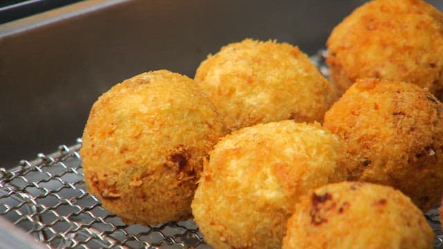 Crispy, golden potato croquettes in a metal container