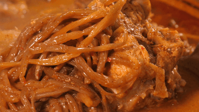 One ladle of pork backbone stew topped with sweet potato stems