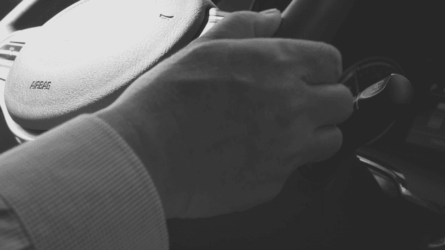 A hand gripping a car steering wheel