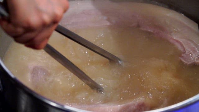 집게로 삶은 돼지고기를 꺼내는 장면