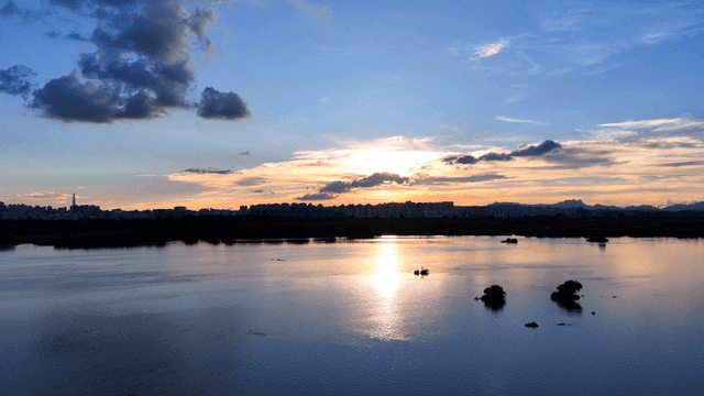 Sunset over a calm river with city skyline
