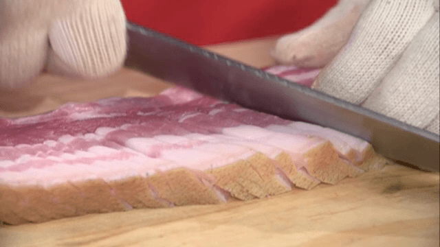 나무 도마 위에서 빠르게 돼지고기 자르기