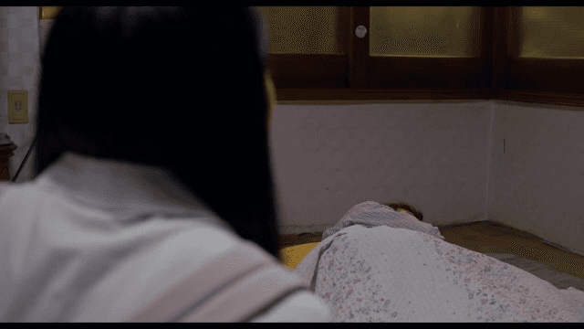 이불을 덮고 누워서 쉬는 노인