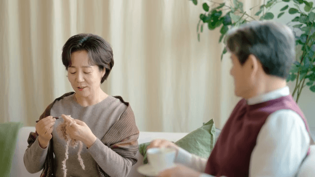 Two elderly people enjoying tea and knitting
