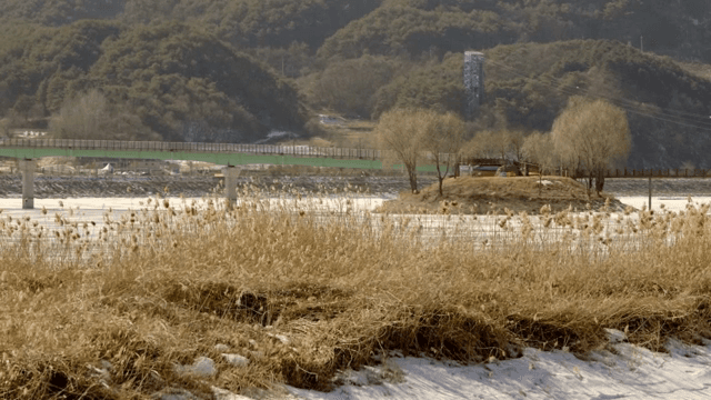 Frozen river with bridge and mountains in view