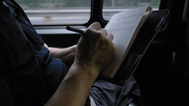 Person writing notes in a moving vehicle