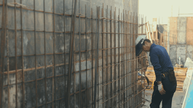 Construction worker inspecting rebar wall