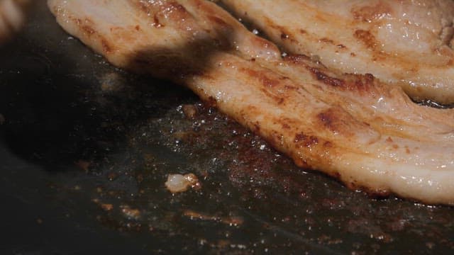 Grilling pork belly slices on a pan