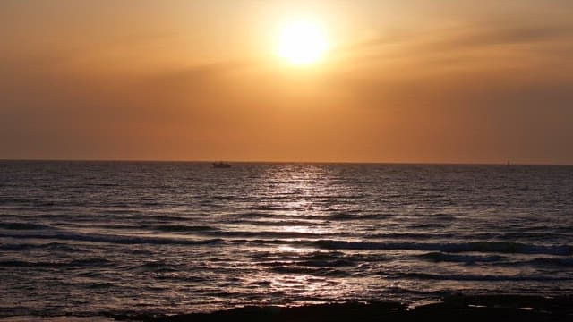 Sunset over the ocean with a distant boat