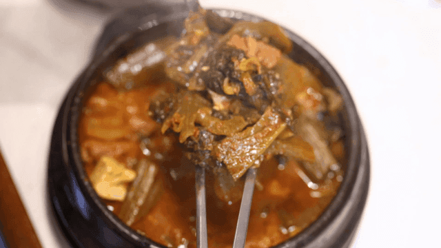 Hot kimchi stew with chopsticks lifting gatgimchi