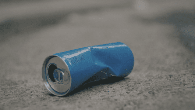 포장도로 위에 찌그러진 파란색 캔