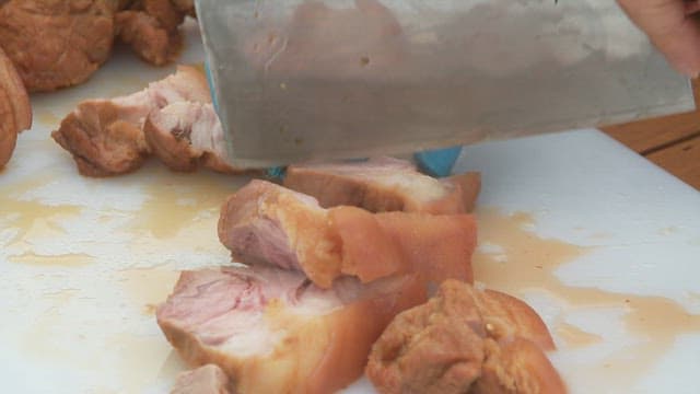 Slicing cooked braised pork meat on a cutting board