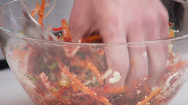 Red pepper powder and various vegetables are mixing in glass bowl