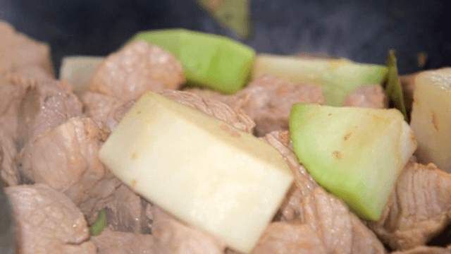 뜨거운 웍에 깍둑썰기한 고기와 무를 볶기