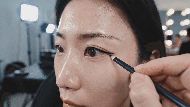 Woman applying eyeliner to her eyes