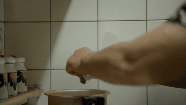 An elderly woman cooking in a kitchen