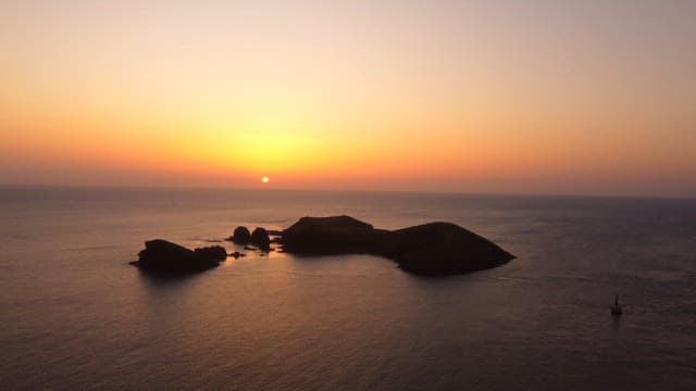 섬이 있는 고요한 바다 위의 일몰