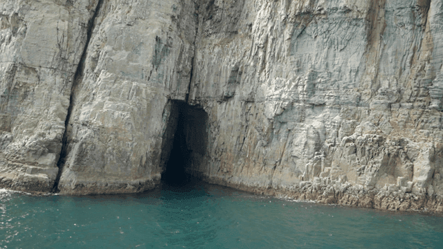 Sea with rocky cliffs and dark cave entrance