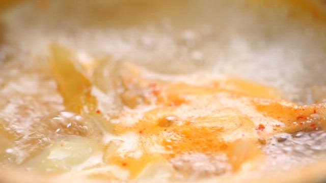 Adding minced garlic to the boiling soup