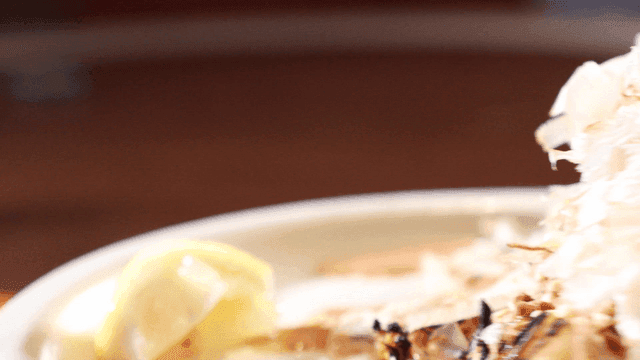 Grilled cabbage topped with bonito flakes and nuts