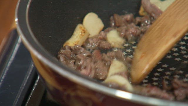 프라이팬에서 마늘을 얹어 요리하는 소고기