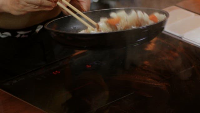 Cooking stir-fried vegetables and meat in a frying pan indoors