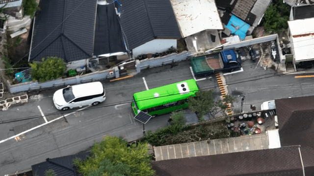 좁은 골목을 지나는 녹색 버스