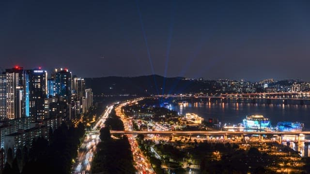 강가 근처의 활기찬 교통과 불이 켜진 고층 건물로 가득한 밤의 분주한 도시 풍경