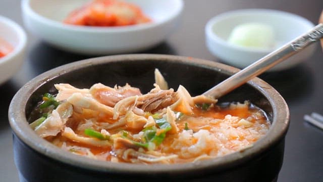 Stirring spicy chicken soup with spoon