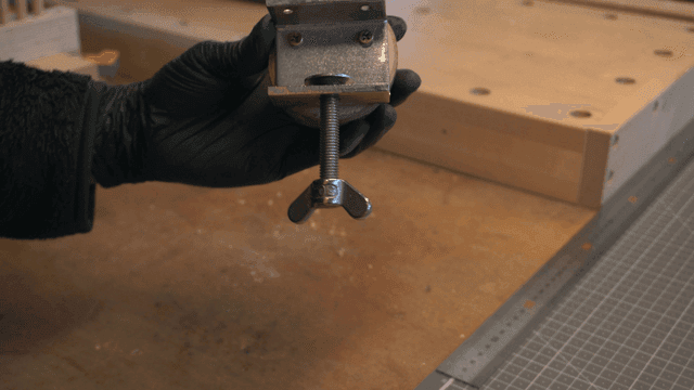 나무 토막과 연결된 브래킷을 들고 있는 손