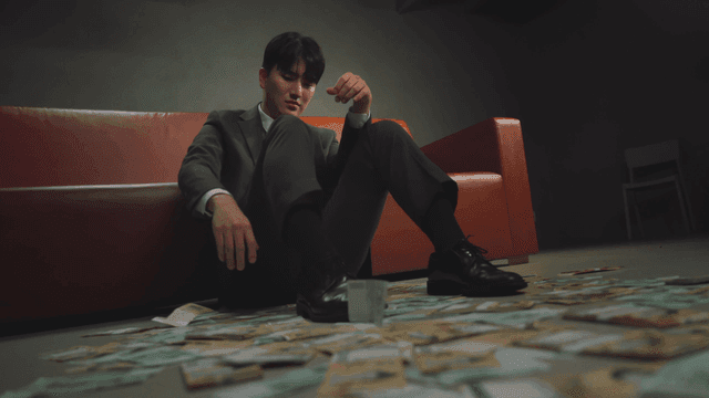 돈과 함께 바닥에 앉아 있는 정장 남성