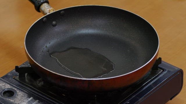 Cooking meat rolls with green onions in a frying pan