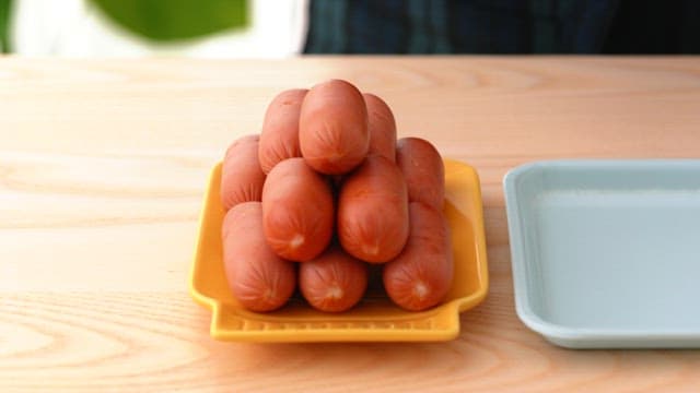 Arranged sausages on a yellow plate on a wooden table