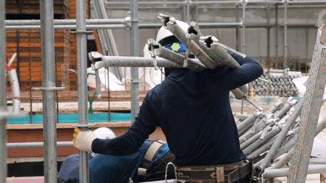 Construction workers carrying metal pipes
