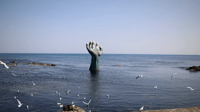 갈매기와 함께 바다에 있는 큰 손 조각상