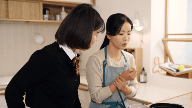 Daughter worries about her mother's wrist pain from moving soup in kitchen.