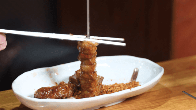 Lamb skewers being removed from skewer with chopsticks